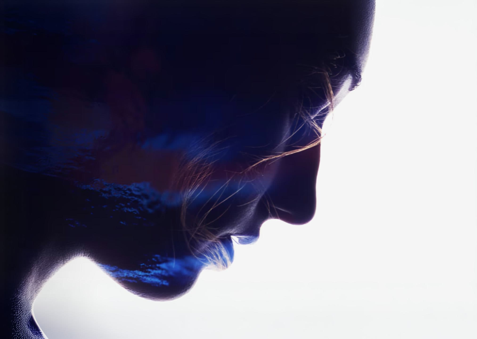 A profile in shadow, lit blue